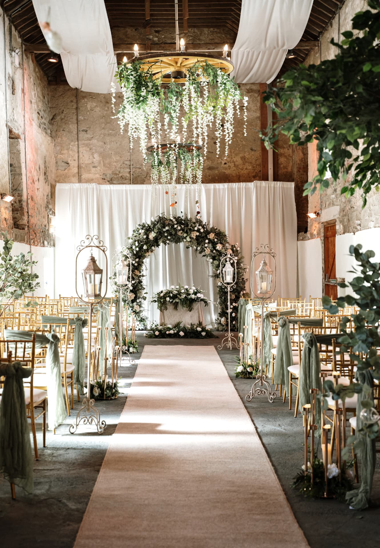 Barn ceremony aisle with floral arch and hanging greenery