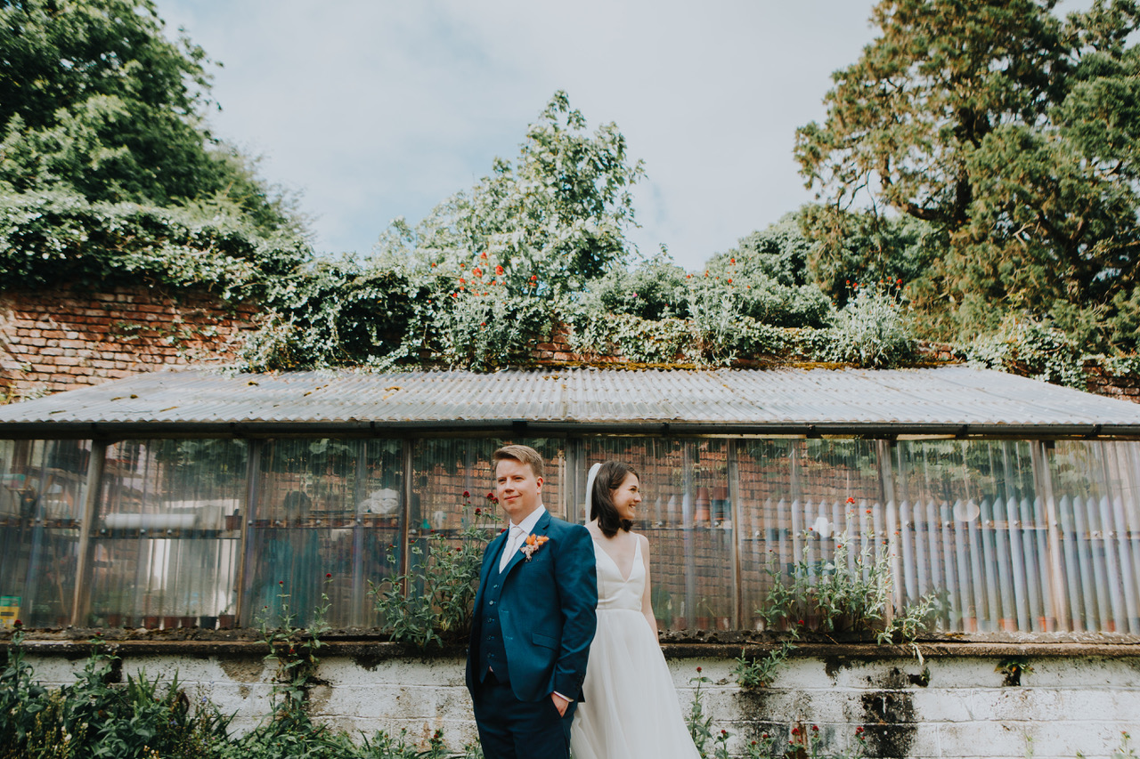 Couple standing in front of the old walled-garden glasshouse
